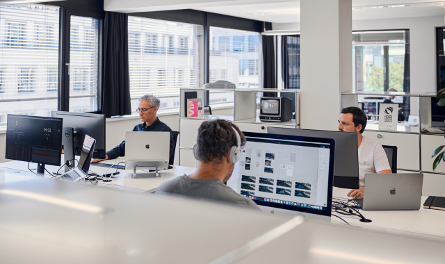 drei-männliche-mitarbeiter-von-studiokurbos-an-Computerbildschirmen-minimalistischer-Raum