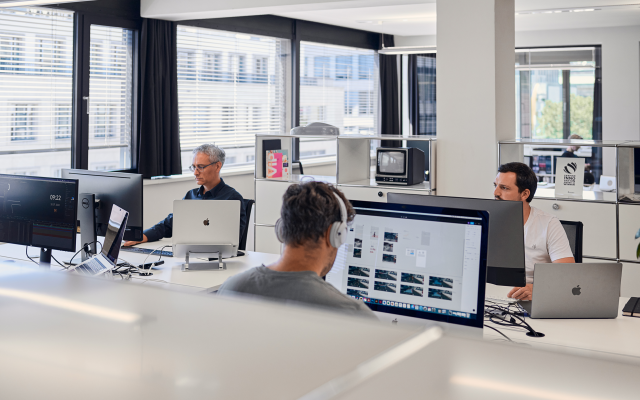 drei-männliche-mitarbeiter-von-studiokurbos-an-Computerbildschirmen-minimalistischer-Raum