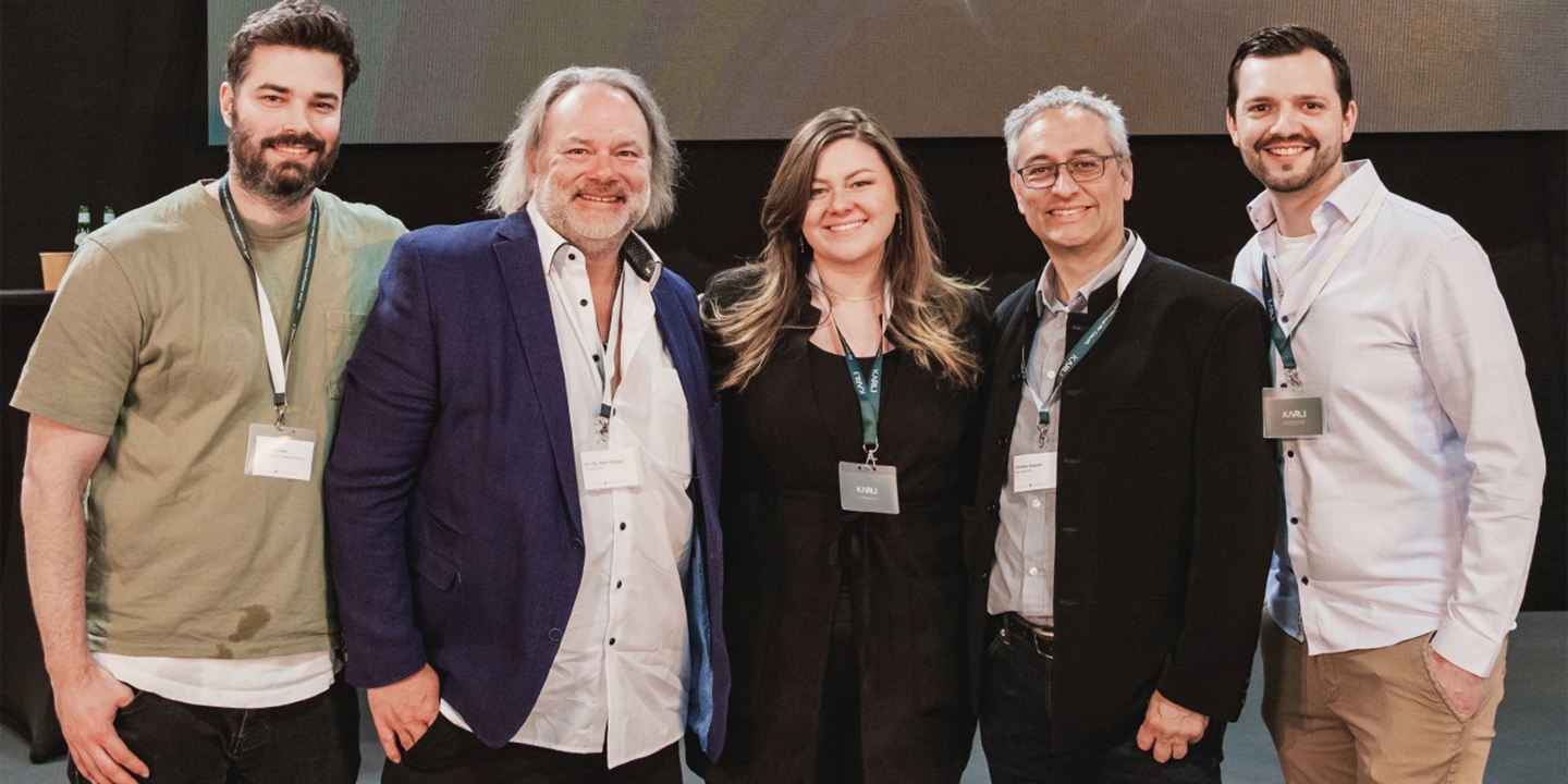 five-people-stand-in-front-of-the-screen-of-an-event-four-men-one-woman-this-is-the-team-from-studiokurbos
