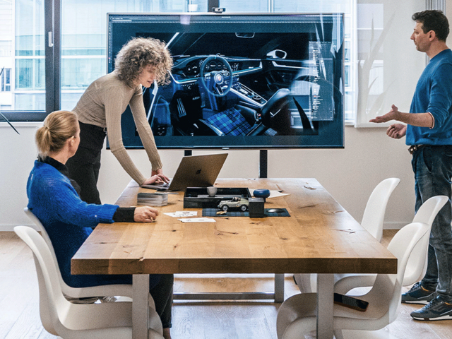 Meeting-room-with-table-and-screen-two-women-and-one-man-talking