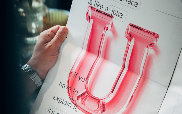 A-male-hand-holds-magazine-No-6-with-a-glass-U-as-a-graphic-on-it